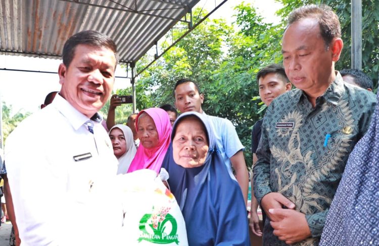 Bupati Simalungun Radiapoh Hasiholan Sinaga saat menyerahkan beras cadangan pangan 2023 kepada salah seorang penerima manfaat.(nawasenanews/Ist)