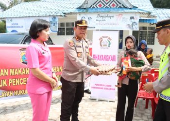 Kapolres didampingi Ketua Bhayangkari Kabupaten Simalungun memberikan makanan tambahan kepada salah satu anak asuh di Silau malaha. ( Nawasenanews/ Ist)