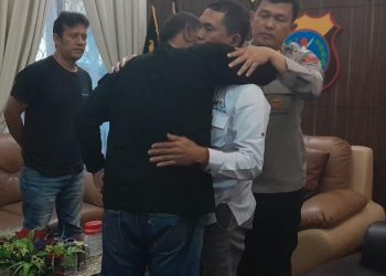 Korban Heriyanto Dolok Saribu dipeluk Samsudin Sigiro ( terduga pelaku penganiayaan wartawan di kota Parapat) disaksikan Kapolres Simalungun Ronald FC Sipayung untuk berdamai dan saling memaafkan. (Nawasenanews/ Ist )