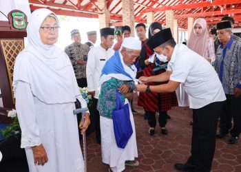 Pj Sekda Pematang Siantar memakaikan seragam jemaah haji secara simbolis dalam acara tepung tawar calon Jemaah Haji di rumah dinas wali kota. ( Nawasenanews/ Ist)