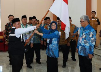 Wali Kota Pematang Siantar dr Susanti menyerahkan pataka bendera merah putih kepada Ketua Kloter 7, saat memberangkatkan jamaah calon haji dari Asrama Haji Pangkalan Masyur Medan,Selasa(30/5/2023).(Nawasenanews/Ist)