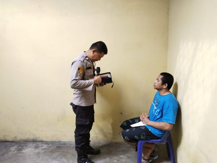 Salah seorang tahanan Polsek Tanah Jawa dibimbing berdoa di sel tahanan sebagai bagian dari pembinaan rohani dan mental yang dipimpin Aiptu J Manihuruk. ( Nawasenanews/ Ist)