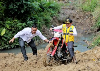 Bupati Simalungun saat berusaha melewati jalan penuh lumpur pada peninjauan jalan yang baru dibuka dengan TMMD 2023 Kodim 0207/ Sml yang menghubungkan Nagori Mekar Sari Panei- Nagori Manik Maraja Sidamanik.( Nawasenanews/ Ist)