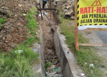 Keterangan foto : Tukang proyek pembangunan Pengelolaan dan Pengembangan Sistem Drainase saat sedang bekerja menggunakan material bekas.(Nawasena.com/AS)