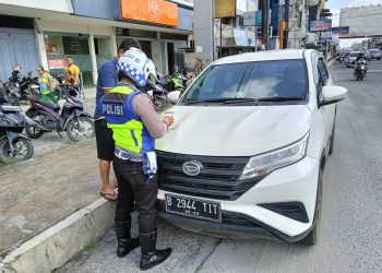 Keterangan Foto : Personil Satlantas melakukan tindakan tegas berupa tilang terhadap tiga unit mobil pribadi di Jalan Sutomo yang parkir di pinggir jalan dengan melanggar rambu larangan parkir.(Ist)