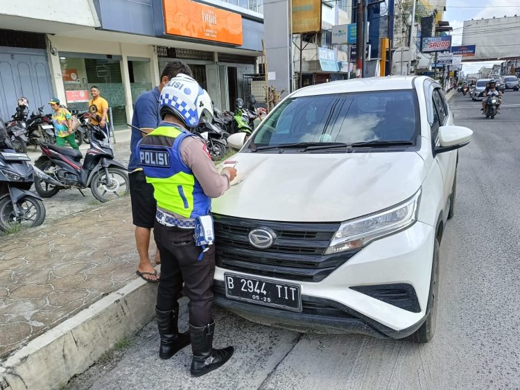 Keterangan Foto : Personil Satlantas melakukan tindakan tegas berupa tilang terhadap tiga unit mobil pribadi di Jalan Sutomo yang parkir di pinggir jalan dengan melanggar rambu larangan parkir.(Ist)